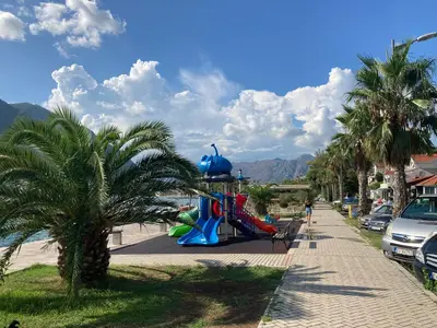 a playground on a beach with a palm tree at Mystras Apartments in Kotor