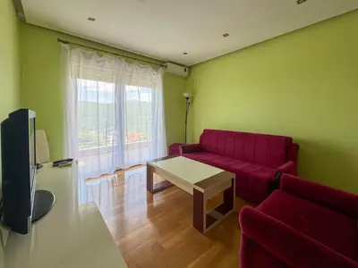 a living room with a red couch and a table at One-bedroom Apart, with panoramic view, Prijevor in Prijevor