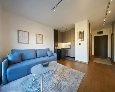a living room with a blue couch and a table at Montenegro Luxury Studio - Hill Homes in Podgorica