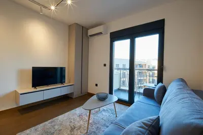 a living room with a blue couch and a flat screen tv at Montenegro Luxury Studio - Hill Homes in Podgorica
