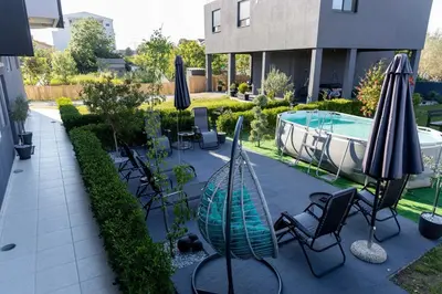 a patio with chairs and umbrellas next to a pool at Sunshine Apartments in Ulcinj
