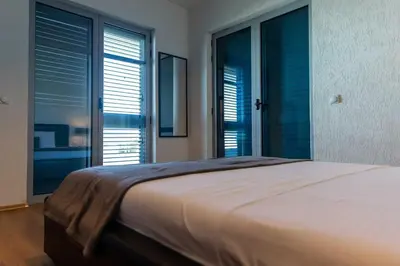 a bedroom with a large bed and large windows at Sunshine Apartments in Ulcinj