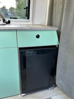 a kitchen with a black dishwasher under a counter at Eagle's path campers Montenegro in Podgorica