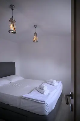a white bed with two lights and towels on it at Apartments Danica in Petrovac na Moru