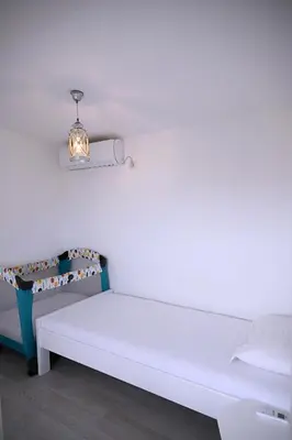 a white bed with a light on a wall at Apartments Danica in Petrovac na Moru