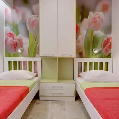 two beds in a room with a painting of pink tulips at Apartments Danica in Petrovac na Moru