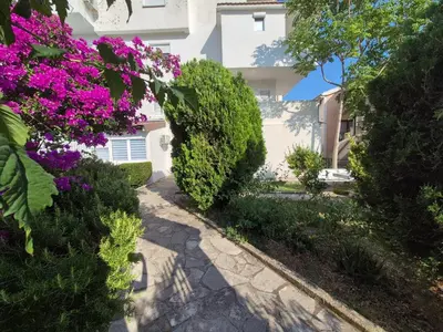 a walkway in front of a building with purple flowers at Cozy apartment in Petrovac in Petrovac na Moru