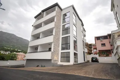 a white apartment building with a parking lot at Studio Dobra Voda 4 in Dobra Voda