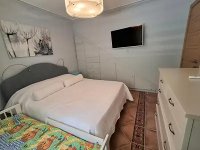 a small bedroom with a bed and a flat screen tv at Beachfront Four Bedroom Apartment in Sveti Stefan