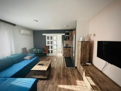 a living room with a blue couch and a tv at Svetli dom in Sutomore