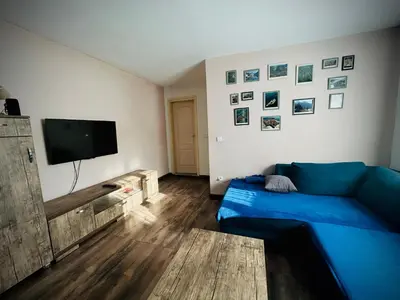 a living room with a blue couch and a flat screen tv at Svetli dom in Sutomore