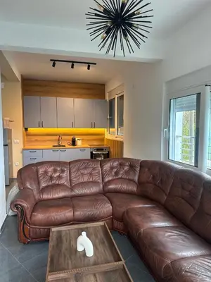a living room with a brown leather couch and a table at La Mer Beach Residence in Ulcinj