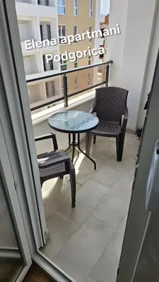 a table and chairs in a room with a window at Elena apartmani Podgorica in Podgorica