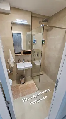 a bathroom with a glass shower and a sink at Elena apartmani Podgorica in Podgorica