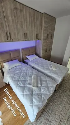 a large bed in a room with wooden cabinets at Elena apartmani Podgorica in Podgorica