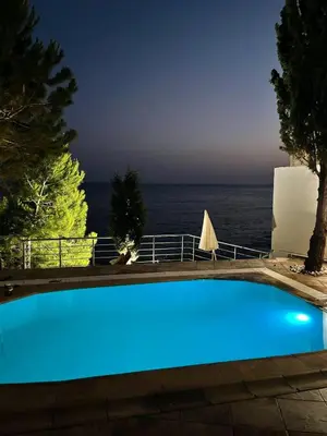a blue swimming pool with the ocean in the background at TALi in Ulcinj