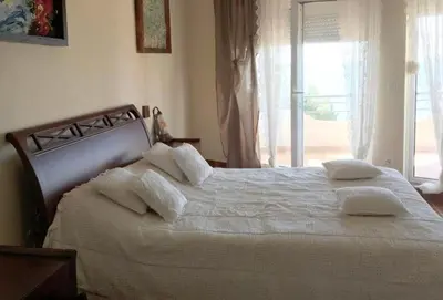 a bedroom with a white bed with pillows and a window at TALi in Ulcinj