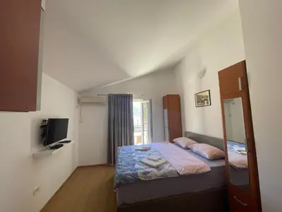 a small bedroom with a bed and a tv at Apartments Manojlovic in Budva