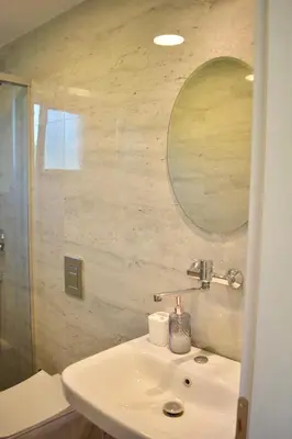 a white bathroom with a sink and a mirror at Tiny House with Hot Tub & View in Ulcinj