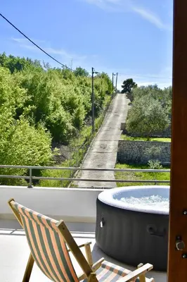 a chair and a tub on a balcony with a road at Tiny House with Hot Tub & View in Ulcinj