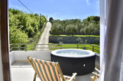 a tub on a balcony with a chair and a road at Tiny House with Hot Tub & View in Ulcinj