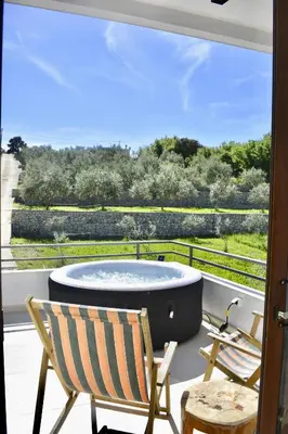 a hot tub sitting on a balcony with two chairs at Tiny House with Hot Tub & View in Ulcinj