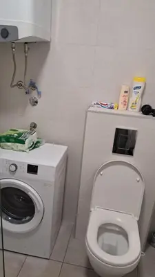a bathroom with a toilet and a washing machine at Studio apartment in Bar