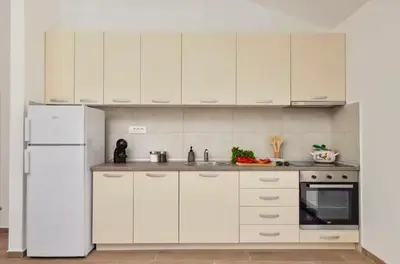 a kitchen with white cabinets and a white refrigerator at Apartmani Nadja in Škaljari