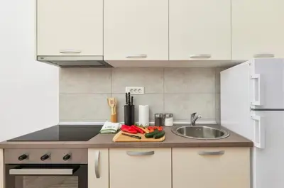a kitchen with white cabinets and a sink at Apartmani Nadja in Škaljari