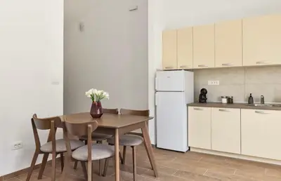 a kitchen with a table and chairs and a white refrigerator at Apartmani Nadja in Škaljari