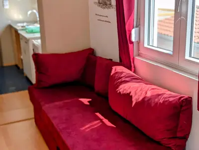a red couch in a room with a window at Sunset Dreams Utjeha in Utjeha
