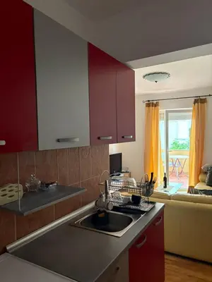 a kitchen with red cabinets and a sink and a couch at Two Bedroom Apartment Budva in Budva
