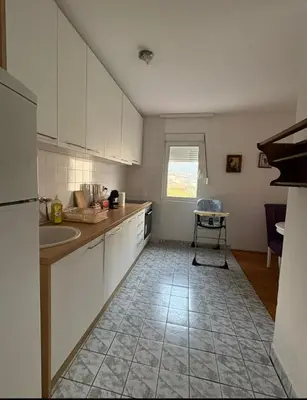 a kitchen with white cabinets and a tile floor at Sea&Sun in Sutomore