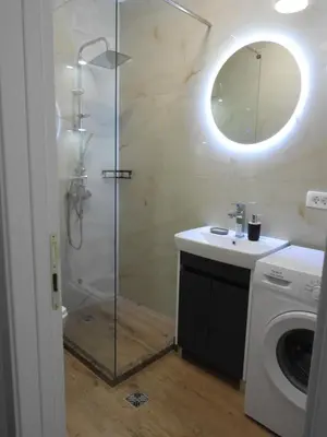 a bathroom with a shower and a washing machine at Boskovic Apartments in Podgorica