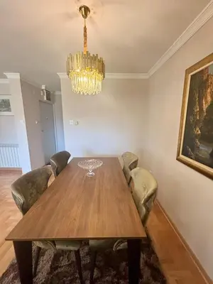 a dining room with a wooden table and a chandelier at Gold Lux in Podgorica