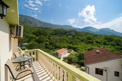 a balcony with a table and chairs and mountains at Guest House Ana in Petrovac na Moru