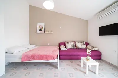 a bedroom with a bed and a purple couch at Guest House Ana in Petrovac na Moru
