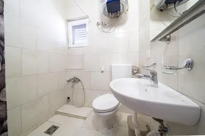 a white bathroom with a toilet and a sink at Guest House Ana in Petrovac na Moru