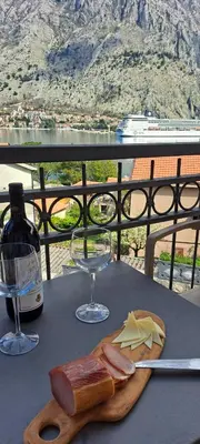 a table with a plate of cheese and a wine glass at Apartment Vujosevic D&D in Kotor