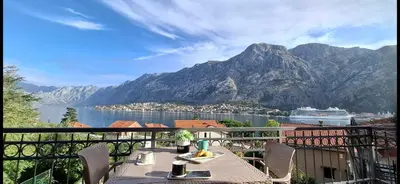 a table on a balcony with a view of a cruise ship at Apartment Vujosevic D&D in Kotor