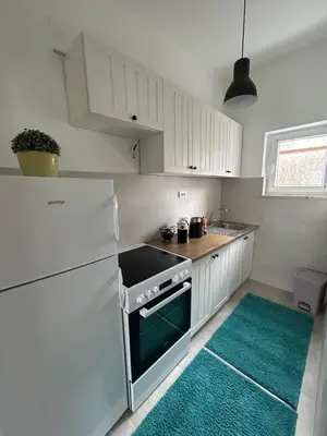 a kitchen with white cabinets and a green rug at Apartment 086 in Cetinje