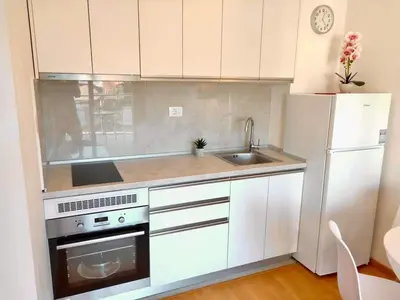 a kitchen with white cabinets and a sink and a refrigerator at Apartments Oliva Mare Budva in Budva