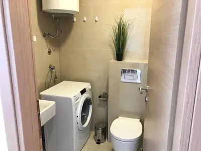 a small bathroom with a washing machine and a toilet at Apartments Oliva Mare Budva in Budva
