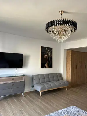 a living room with a couch and a chandelier at Fusion Apartment in Dobra Voda