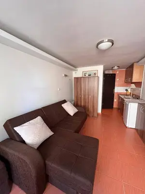 a living room with a brown couch and a kitchen at Garsonjera in Kravlja
