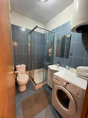 a bathroom with a shower and a toilet and a washing machine at Quiet Studio Bečići Garage available 5 e per day in Boreti