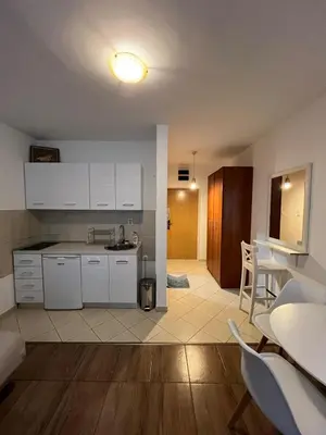 a kitchen with white cabinets and a table and chairs at Quiet Studio Bečići Garage available 5 e per day in Boreti