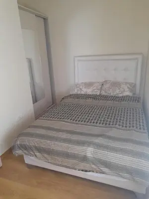 a bed in a white room with a gray blanket at Apart SASHENKA in Bar