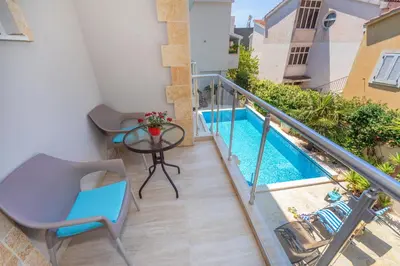 a balcony with a table and chairs and a swimming pool at Apartments Fortunella in Petrovac na Moru
