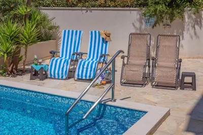 a group of chairs sitting next to a swimming pool at Apartments Fortunella in Petrovac na Moru